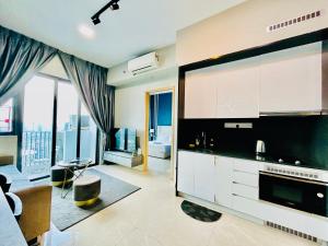 a kitchen with white cabinets and a living room at The Luxe Service Suites in Kuala Lumpur