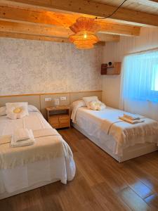 a bedroom with two beds and a chandelier at La casa de Tio Mines in Regolfo