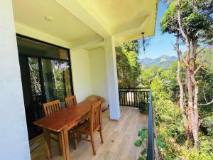 a porch with a wooden table and chairs on a balcony at Ella Mist Haven in Ella