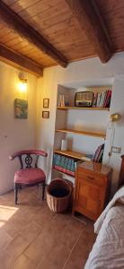 a bedroom with a chair and a shelf with books at Nespello Tourist Accommodation in Costa di Serina