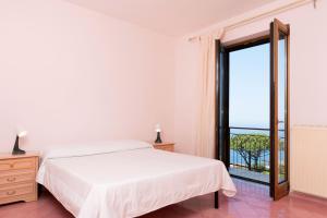 a white bedroom with a bed and a large window at Sunset Capri by Espresso Rentals in Massa Lubrense