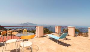 a balcony with chairs and a table and the ocean at Sunset Capri by Espresso Rentals in Massa Lubrense