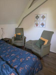 a bedroom with two chairs and a bed and a couch at Herberg de Griffioen in Wolphaartsdijk