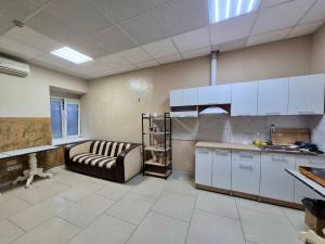 a kitchen with white cabinets and a couch in a room at Podil-House-Hotel in Kyiv