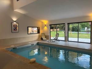 a swimming pool in a house with two chairs in it at Sillage in Machiel