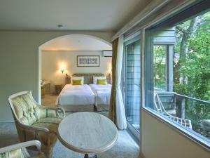 a bedroom with a bed and a table and a balcony at Auberge de Primavera in Karuizawa