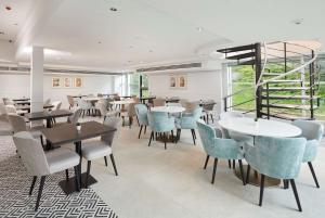 a restaurant with tables and chairs and a staircase at Hilton London Croydon in Croydon +50 photos