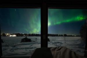 a view of the aurora from a window of a tent at Aurora Lake Lodges in Ranua