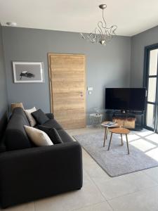 a living room with a black couch and a tv at Schlof'zheim in Friesenheim