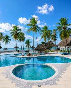 a swimming pool with palm trees and the ocean at Protels La Plage Resort in Bwejuu