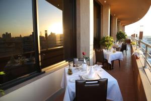 a restaurant with white tables and chairs and a large window at Attawfeek Plaza in Tripoli