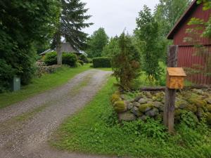 a dirt road next to a barn and a stone wall at Muhu Garden Cabin in Suuremõisa +6 photos