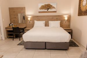 a bedroom with a large bed and a desk at Wilkoppies Self Catering in Klerksdorp