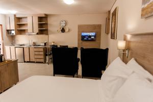 a bedroom with a bed and two chairs and a kitchen at Wilkoppies Self Catering in Klerksdorp