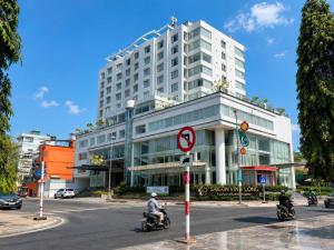 a large building with people riding motorcycles on the street at Khách sạn Sài Gòn Vĩnh Long in Vĩnh Long