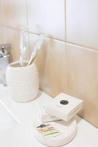 a bathroom counter with a box of tooth brushes and a cup at House Santa Rita in Turin