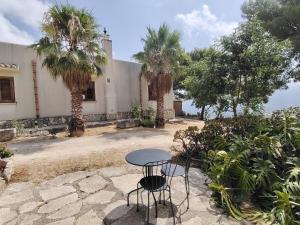 a table and two chairs in a courtyard with palm trees at Agriturismo Finazzo in Balata di Baida