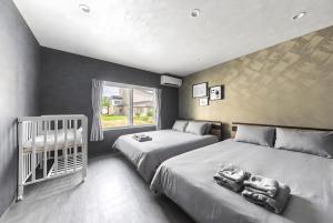 a bedroom with two beds and a crib in it at The Elements in Nakafurano