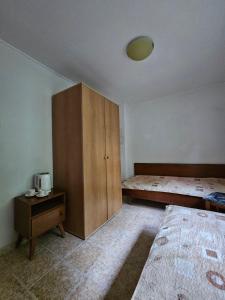 a bedroom with a bed and a wooden cabinet at Къщи за гости Кедър in Varna City