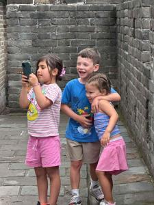 a group of three children standing next to a brick wall at BeiJing Mutianyu Hills Pool Wall Resort view at the foot of Mutianyu Great Wall, infinity pool, one-way PEK airport pick-up, free laundry and coffee in Huairou