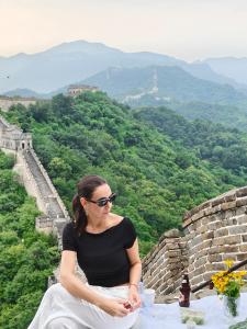 a woman sitting on the edge of the great wall at BeiJing Mutianyu Hills Pool Wall Resort view at the foot of Mutianyu Great Wall, infinity pool, one-way PEK airport pick-up, free laundry and coffee in Huairou