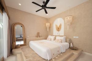 a bedroom with a large bed with a ceiling fan at Gili Boho Villas - Aesthetic Private Pool Villas in Gili Trawangan