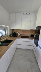 a white kitchen with wooden counters and white cabinets at Vila Castrum in Nové Zámky +16 photos