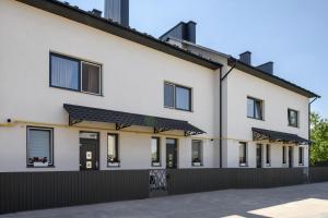 a white house with black doors and a black fence at Апарт готель Метрополь in Chernivtsi