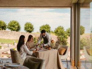 Eine Gruppe von Menschen sitzt mit Weingläsern um einen Tisch. in der Unterkunft Palacio de Luces, Small Luxury Hotels in Luces
