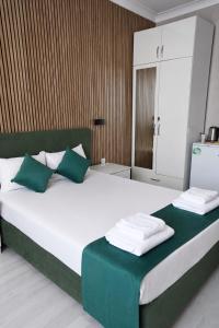 ein Schlafzimmer mit einem großen Bett und grünen und weißen Kissen in der Unterkunft DORA BEYTEPE HoTEL in Çayyolu