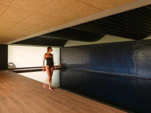 Eine Frau in einem schwarzen Kleid steht neben einem Schwimmbecken. in der Unterkunft Palacio de Luces, Small Luxury Hotels in Luces