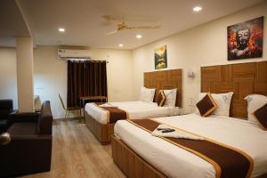 a hotel room with two beds and a chair at Hotel Savithas Grand in Vijayawāda