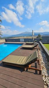 a swimming pool with two chaise lounges on a wooden deck at Pine View Guesthouse Graskop in Graskop