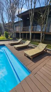 a swimming pool with chaise lounges next to a building at Pine View Guesthouse Graskop in Graskop