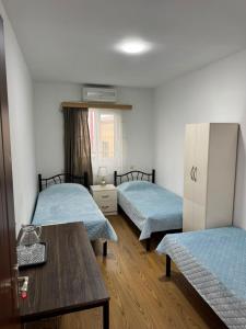 a room with two beds and a wooden table at NAPO HOTEL სასტუმრო ნაპო in Zugdidi
