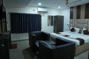 a hotel room with a bed and a chair at Hotel Savithas Grand in Vijayawāda