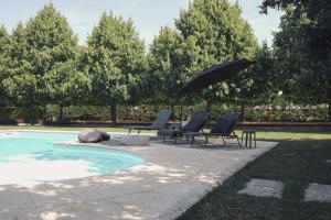 a patio with chairs and an umbrella next to a pool at Villa Anastasia in Carpi