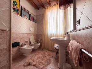 a bathroom with a white toilet and a sink at Villa Anastasia in Carpi