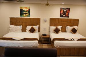 a room with two beds and a tv in it at Hotel Savithas Grand in Vijayawāda