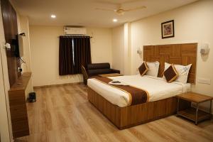 a hotel room with a bed and a chair at Hotel Savithas Grand in Vijayawāda
