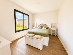 a white bedroom with a bed and a window at Le Clos de Luc - 3 chambres - Jardin - Plage à 5 min in Luc-sur-Mer