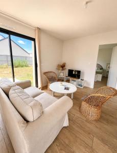 a living room with a couch and a table at Le Clos de Luc - 3 chambres - Jardin - Plage à 5 min in Luc-sur-Mer