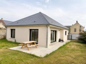 a white house with a picnic table in the yard at Le Clos de Luc - 3 chambres - Jardin - Plage à 5 min in Luc-sur-Mer