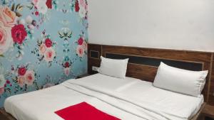 a bedroom with a white bed with a floral wallpaper at Triveni Inn in Jahāngīrābād