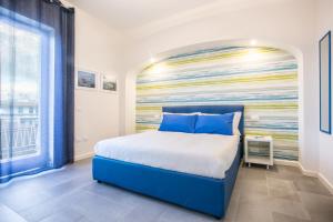 索倫托的住宿－Sorrento Incantata，卧室配有蓝色的床和墙上的绘画作品