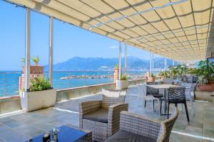 a patio with tables and chairs and a view of the ocean at Hotel Centro Congressi Polo Nautico in Salerno