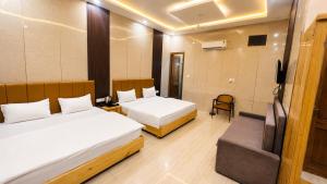 a hotel room with two beds and a television at The Pearl Hotel Rampur in Rāmpur +15 photos