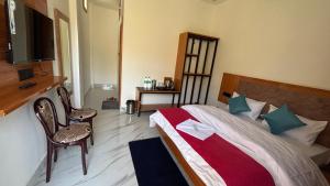 a bedroom with a bed and two chairs and a television at Hotel The SunGod in Uttarkāshi