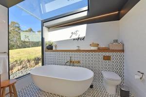 a bathroom with a white tub and a toilet at The Glass Ceiling 360 degree Mount View Hideaway in Mount View