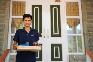 a man holding a box in front of a door at SaffronStays StoneVilla in Shimla +25 photos